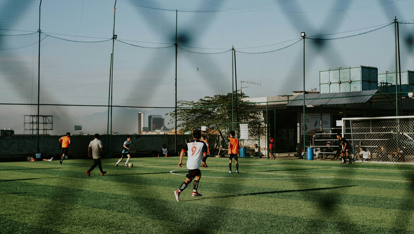 Community members playing football on an open field; illustrative stock photography