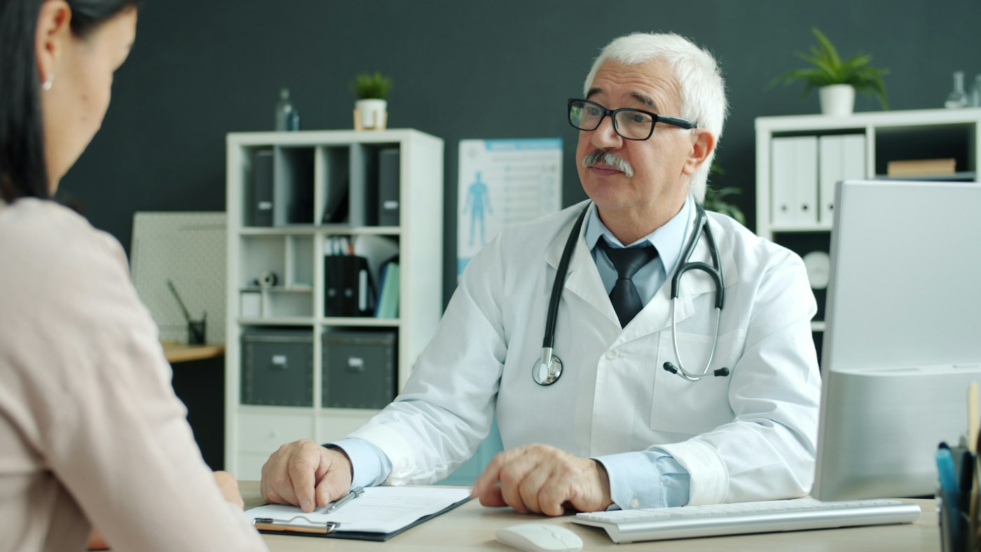 Doctor speaking with a patient in a consultation room; illustrative stock photography
