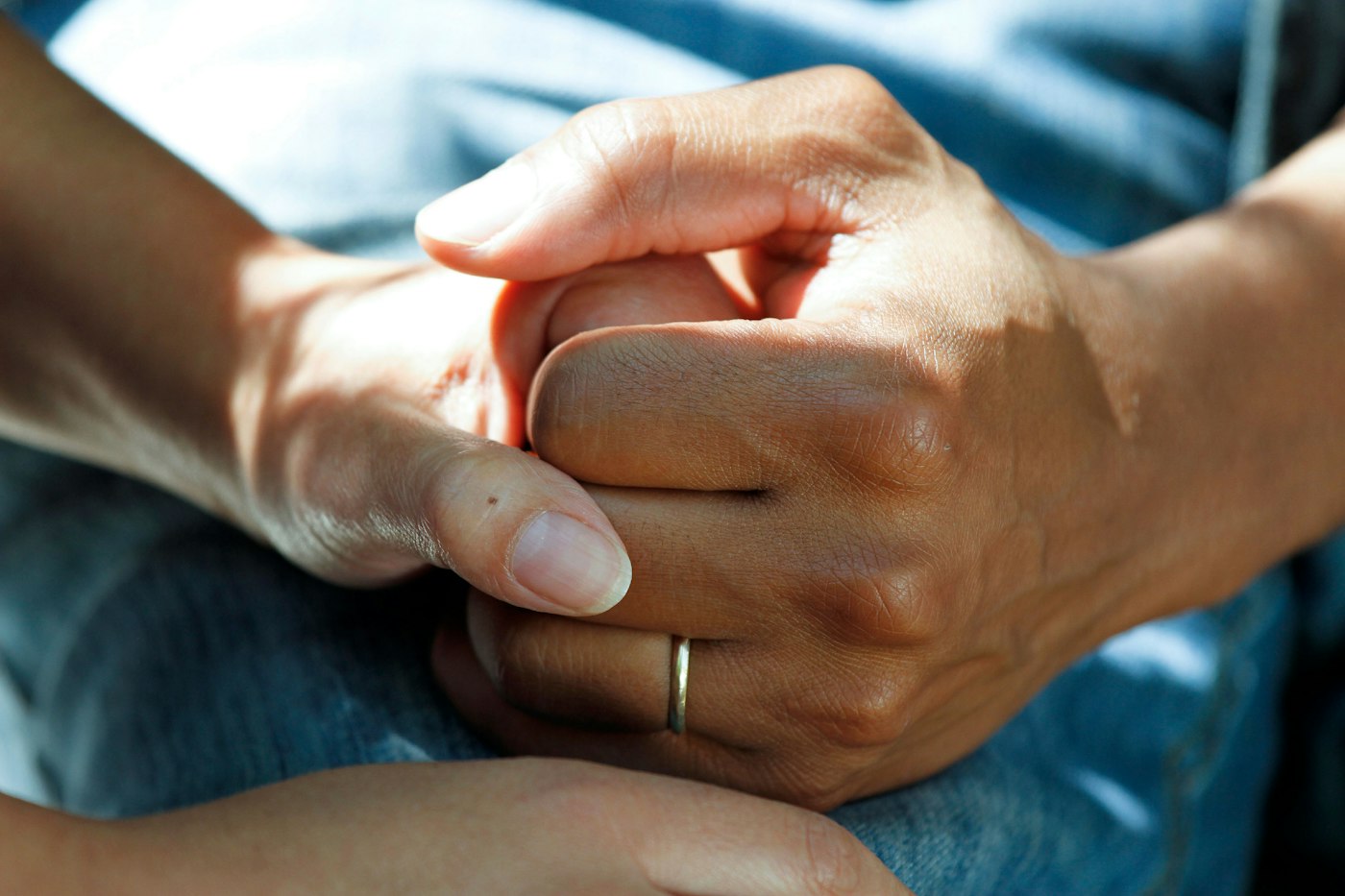 Healthcare worker gently holding a patient’s hand; illustrative stock photography